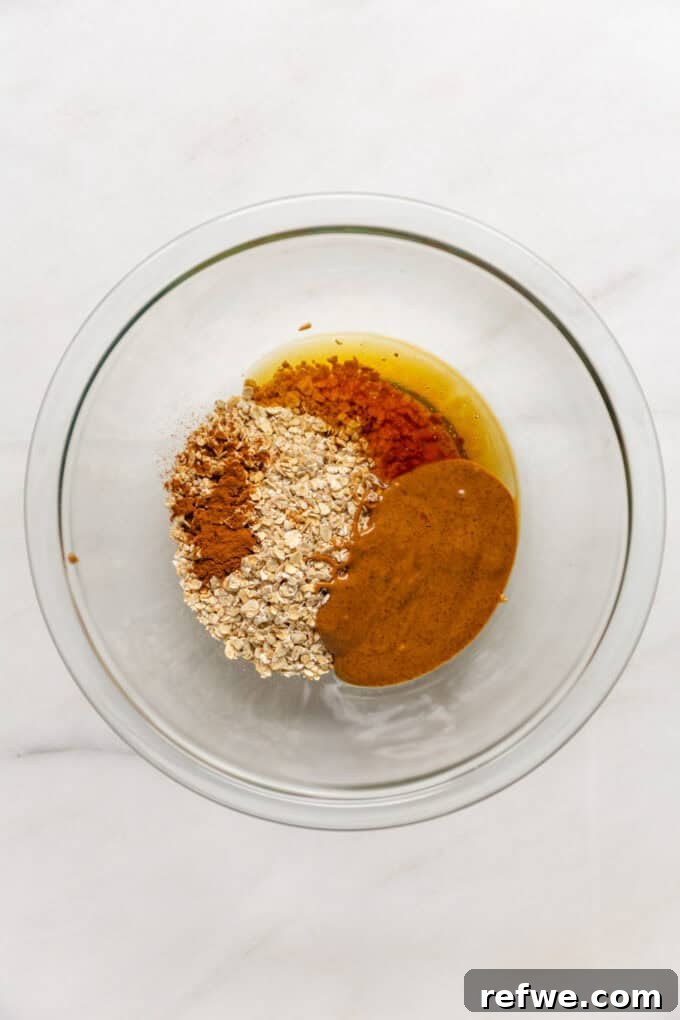 Oats, nut butter, honey, cinnamon, and vanilla extract being mixed in a bowl for the granola crust.