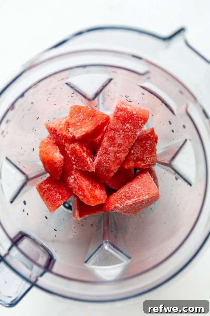 Crimson Crush 4 Close-up of frozen watermelon chunks being placed into a high-speed blender, ready to be transformed into a refreshing slushie.