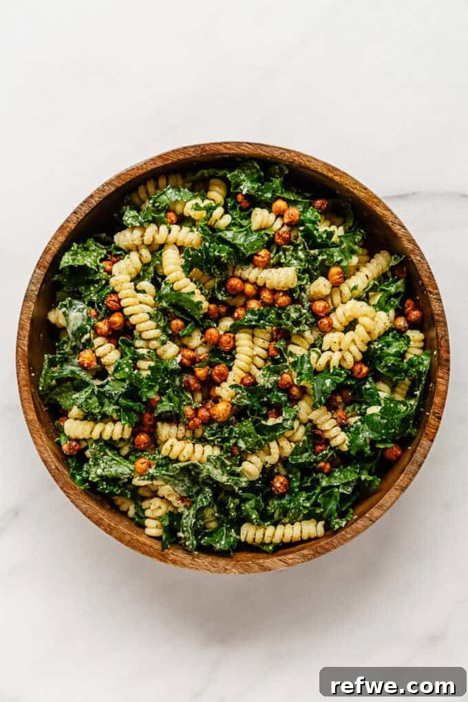 Caesar's Hearty Kale Pasta 11 The fully mixed Kale Caesar Pasta Salad with kale and roasted chickpeas presented in an elegant wooden bowl.