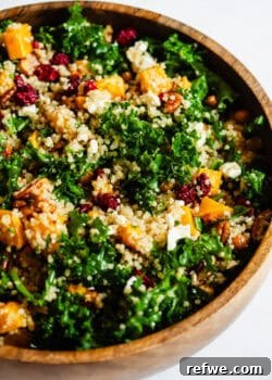 A vibrant roasted butternut squash, kale, and quinoa salad served in a elegant wooden bowl.