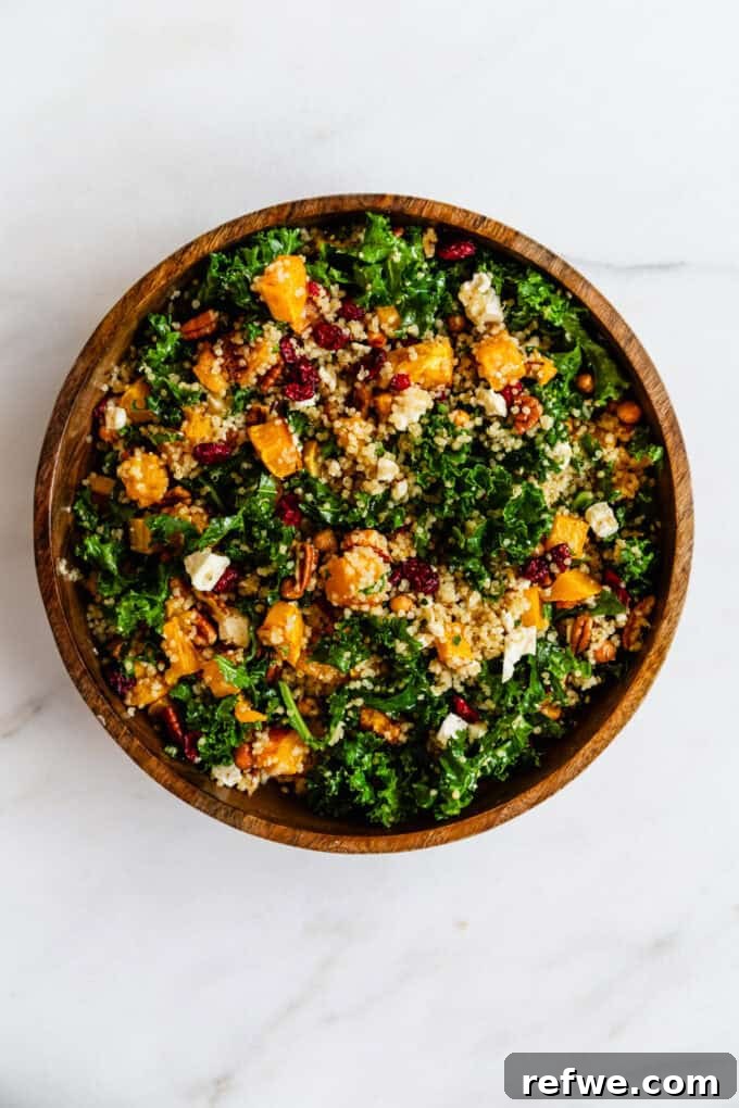 The fully assembled butternut squash and kale salad, tossed with vinaigrette, served in a beautiful wooden bowl, ready to be enjoyed.