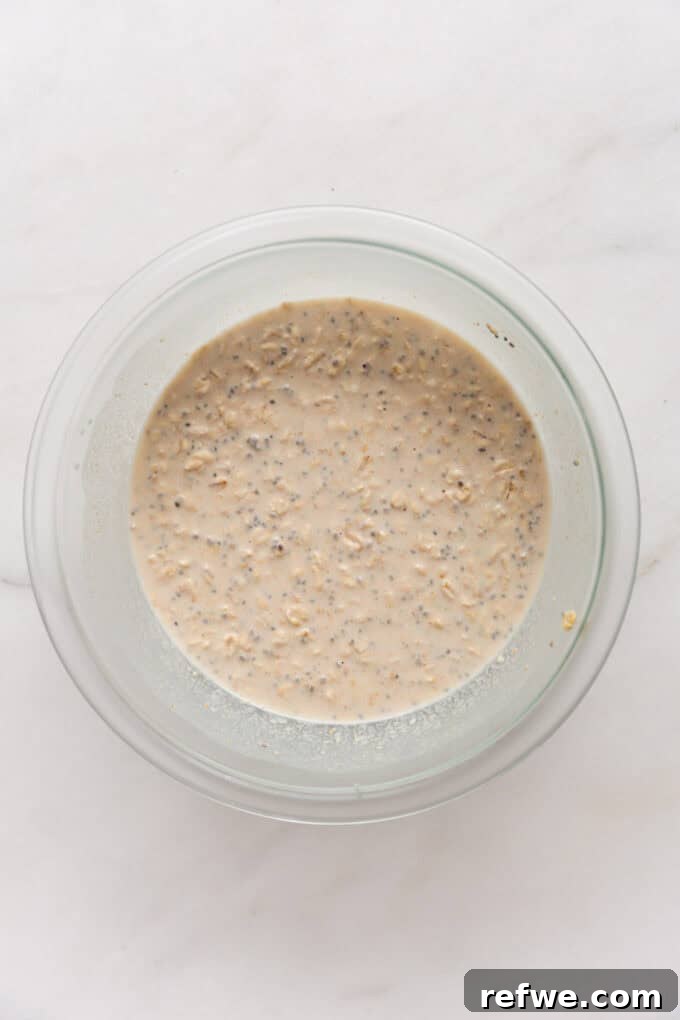 Decadent Snickers Overnight Oats 5 Snickers overnight oats mixture in a clear mixing bowl, ready to be covered and chilled.
