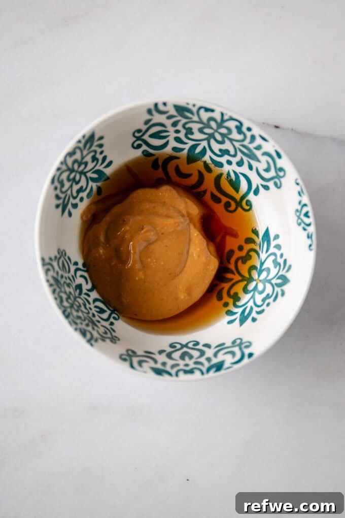 Decadent Snickers Overnight Oats 6 Maple syrup and peanut butter in a small bowl, separate from each other, ready to be mixed for the caramel layer.