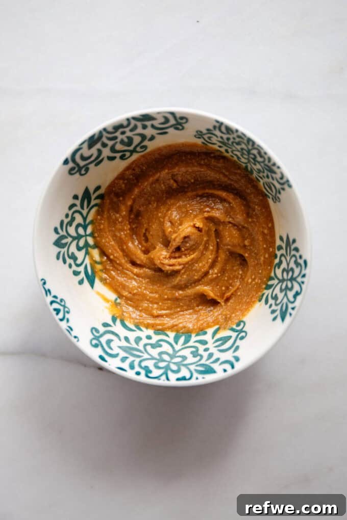 Decadent Snickers Overnight Oats 7 Mixed peanut butter and maple syrup in a small bowl, showing the smooth consistency of the homemade caramel.