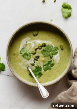 a bowl of broccoli cauliflower soup topped with cilantro and pumpkin seeds