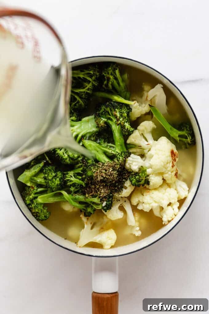 Golden Roasted Cauliflower and Broccoli Bisque 6 broth being poured into a pot of roasted broccoli and cauliflower