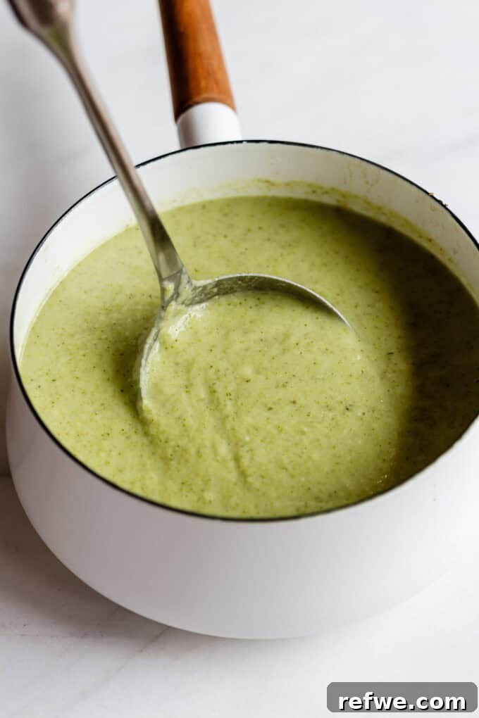 Golden Roasted Cauliflower and Broccoli Bisque 7 a ladle scooping broccoli cauliflower soup out of a white pot