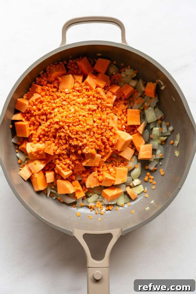 Wholesome Red Lentil Sweet Potato Curry 5 Cubed sweet potatoes and rinsed red lentils are added to the pan with the sautéed aromatics, preparing for the next stage of cooking.