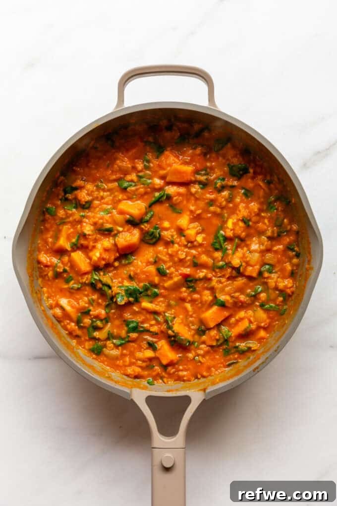 Wholesome Red Lentil Sweet Potato Curry 8 The fully cooked Red Lentil Sweet Potato Curry sits in a taupe pan, rich and ready to be served, awaiting final seasoning.