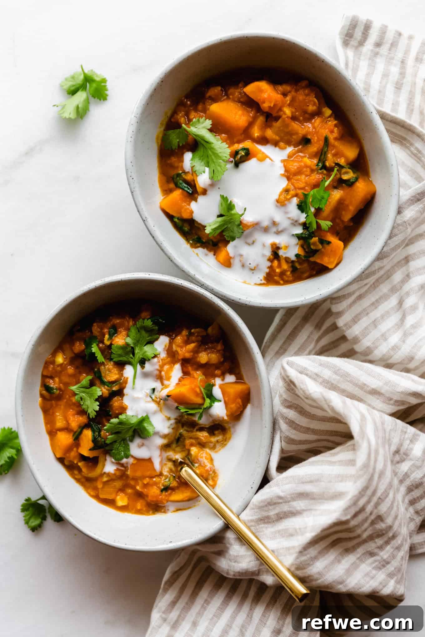 Wholesome Red Lentil Sweet Potato Curry 10 Two enticing bowls of Red Lentil Sweet Potato Curry, artfully drizzled with coconut milk and adorned with fresh cilantro, captured from an overhead perspective.