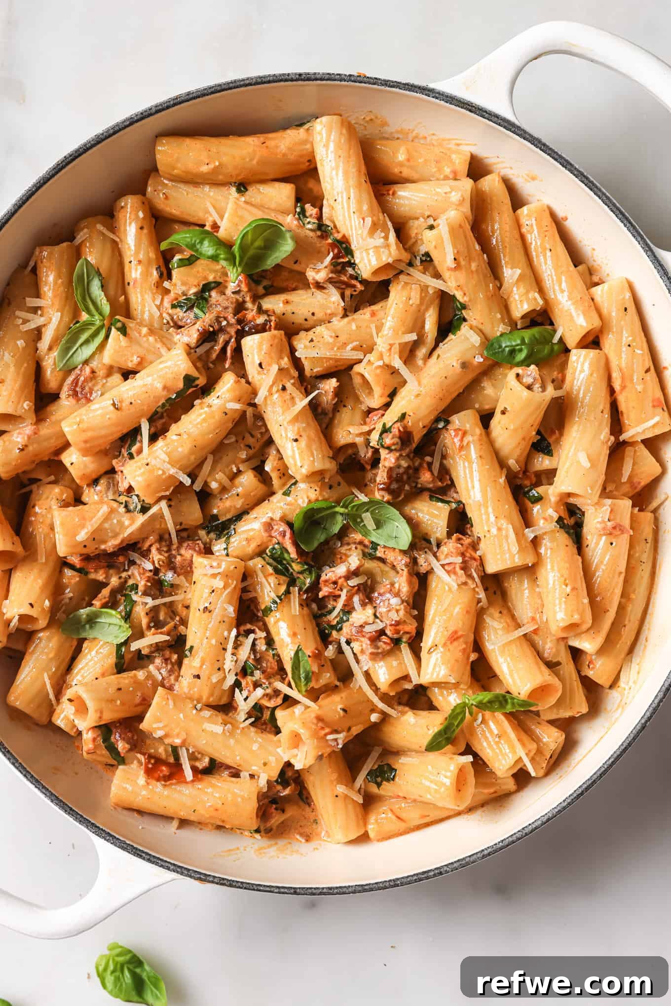 The Proposal Pasta 2 A pot of rigatoni in a vibrant sun-dried tomato sauce, garnished with fresh basil leaves, ready to be served.