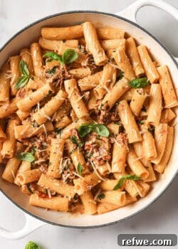 A pot of rigatoni in sun-dried tomato sauce with basil, a close-up.