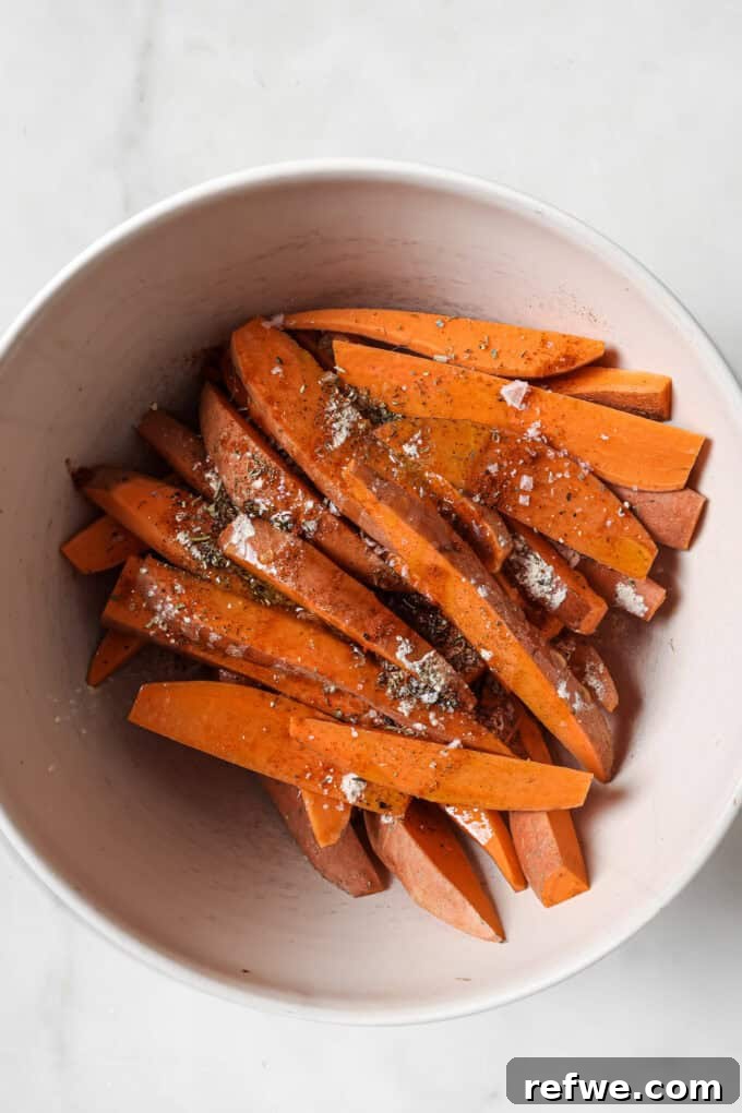 Crispy Air-Fried Sweet Potato Wedges 4 Sweet potatoes being cut into uniform wedges on a cutting board, ready for seasoning