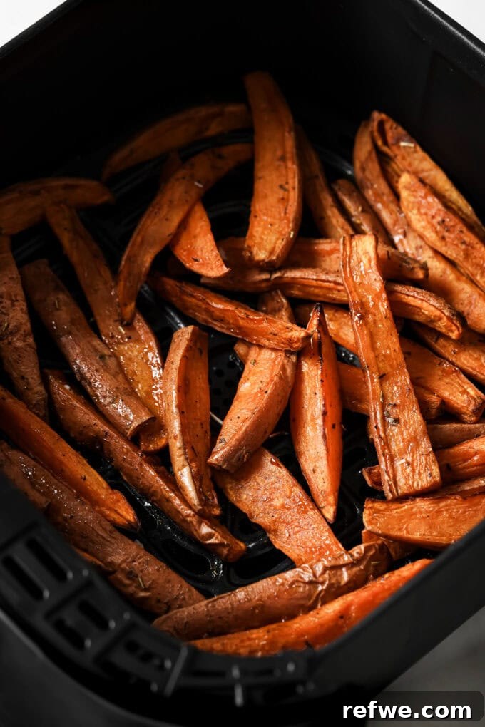 Crispy Air-Fried Sweet Potato Wedges 7 Perfectly cooked, golden-brown crispy sweet potato wedges inside an air fryer basket, just pulled out