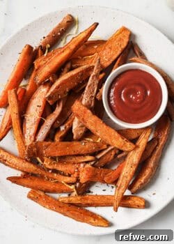 Crispy sweet potato wedges on a white plate with a side of ketchup, ready to be served