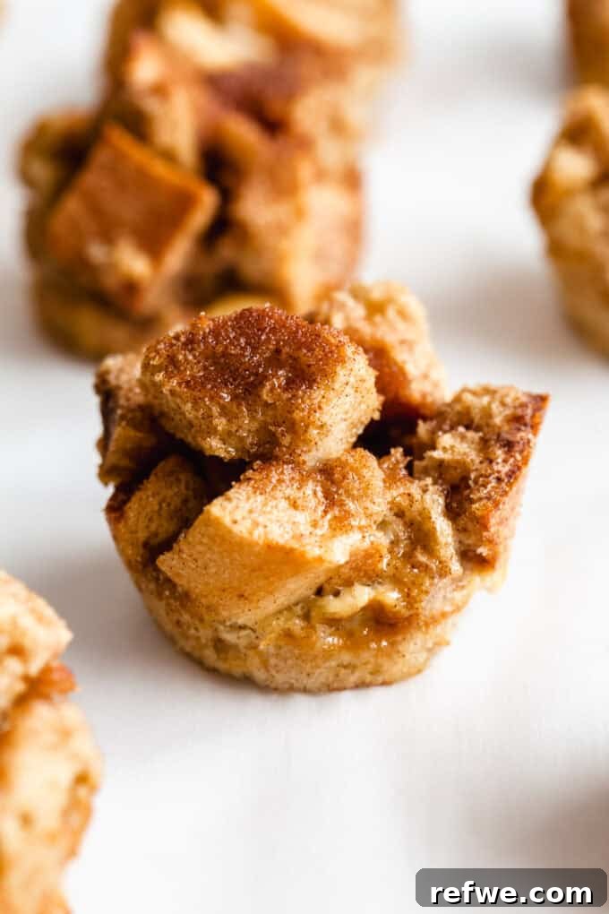 A close-up of a single French toast muffin generously topped with cinnamon sugar, showcasing its perfect golden-brown crust and fluffy interior.