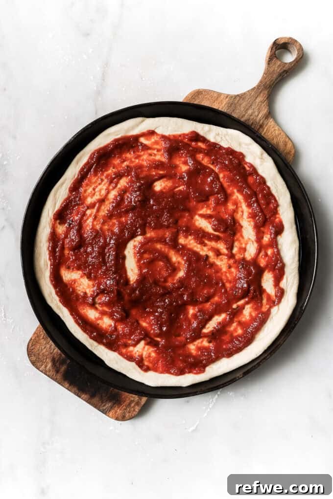 Sun-Kissed Mediterranean Pizza 5 pizza dough topped with pizza sauce on a wood board