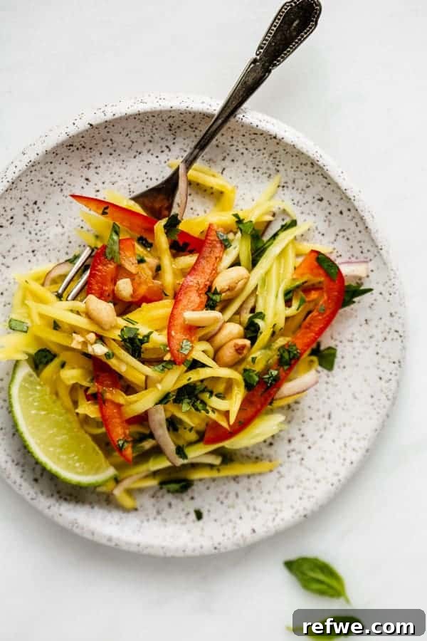Zesty Thai Mango Salad 5 A elegant white plate showcasing a vibrant Thai mango salad, perfectly garnished
