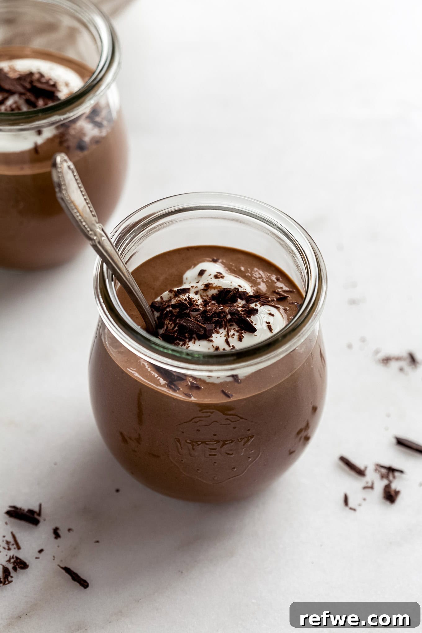 A cup of cottage cheese chocolate mousse topped with yogurt and chocolate shavings.