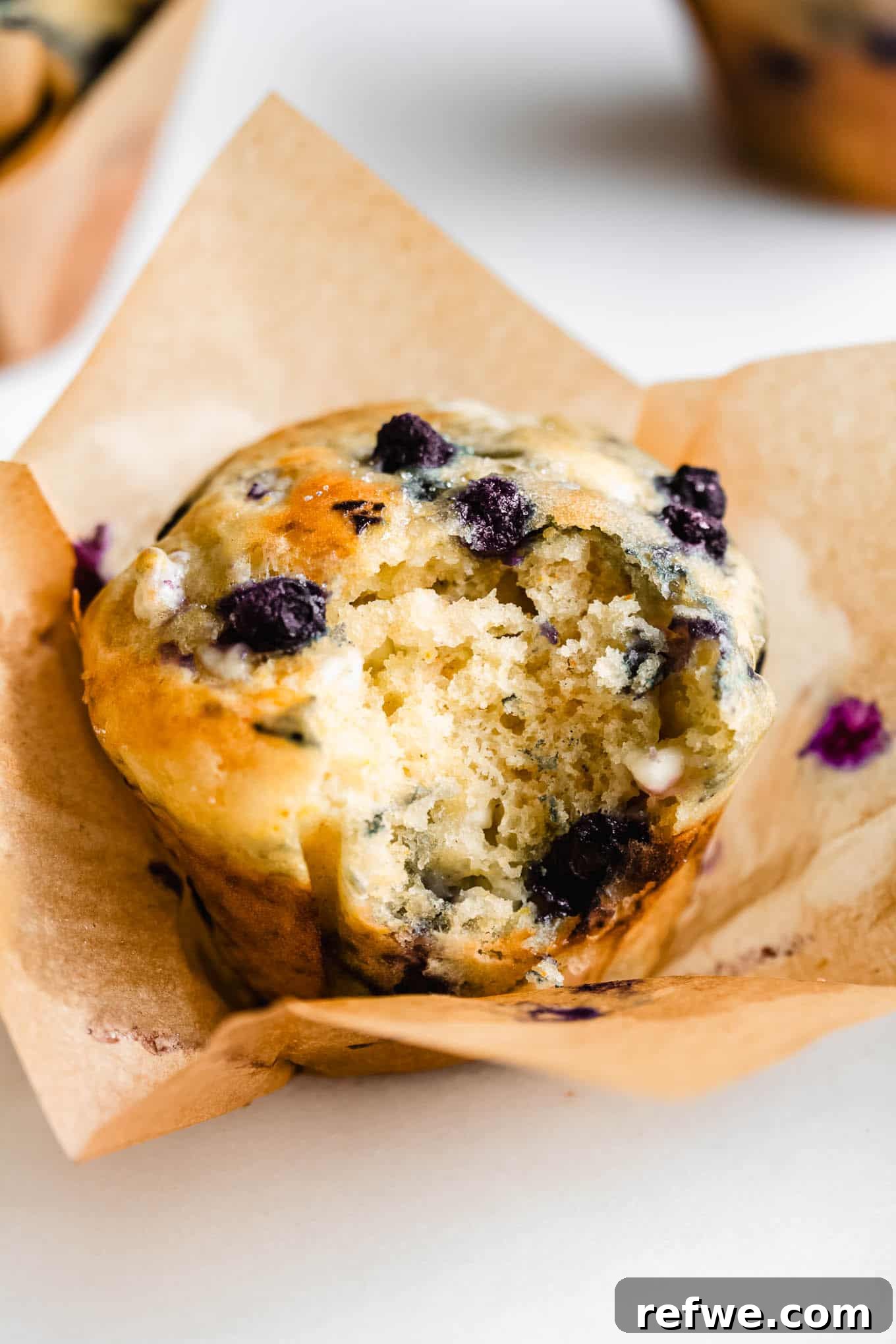 A perfectly baked cottage cheese blueberry muffin with a bite taken out of it, revealing its fluffy interior and scattered blueberries.