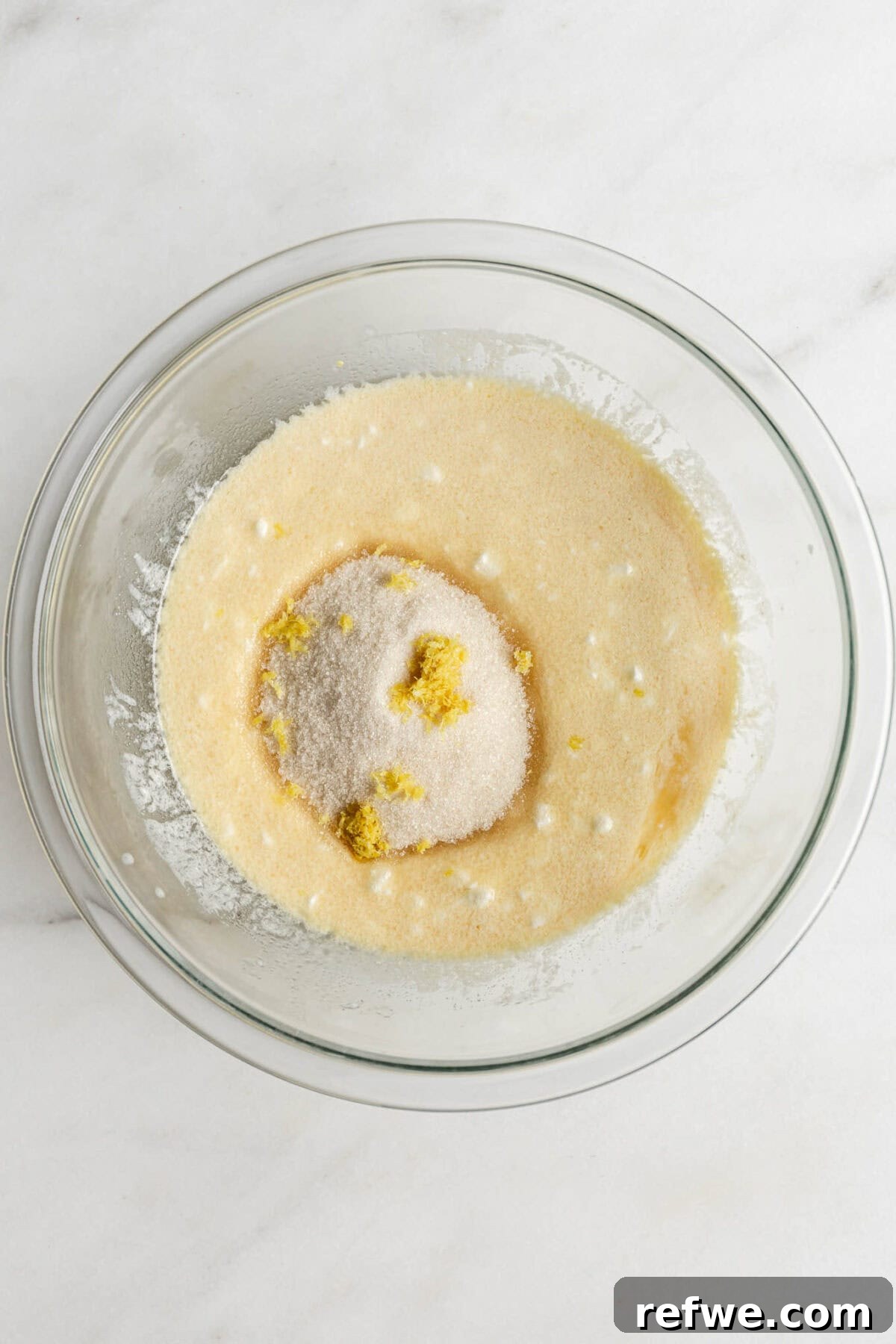 Cottage cheese, milk, egg, oil, and vanilla mixed with sugar and lemon zest in a mixing bowl.