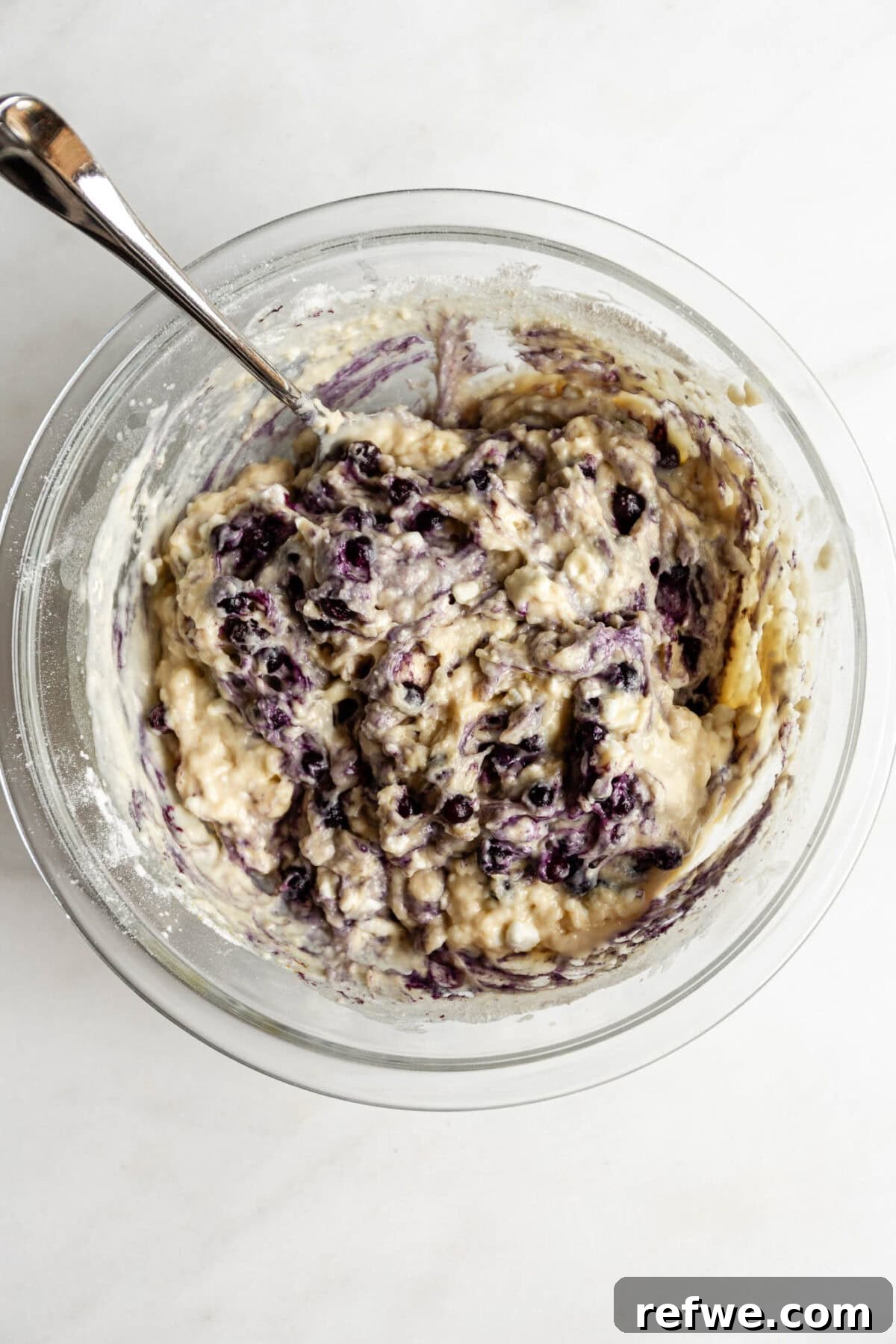 Blueberry cottage cheese muffin batter with blueberries gently folded in, ready for baking, in a mixing bowl.