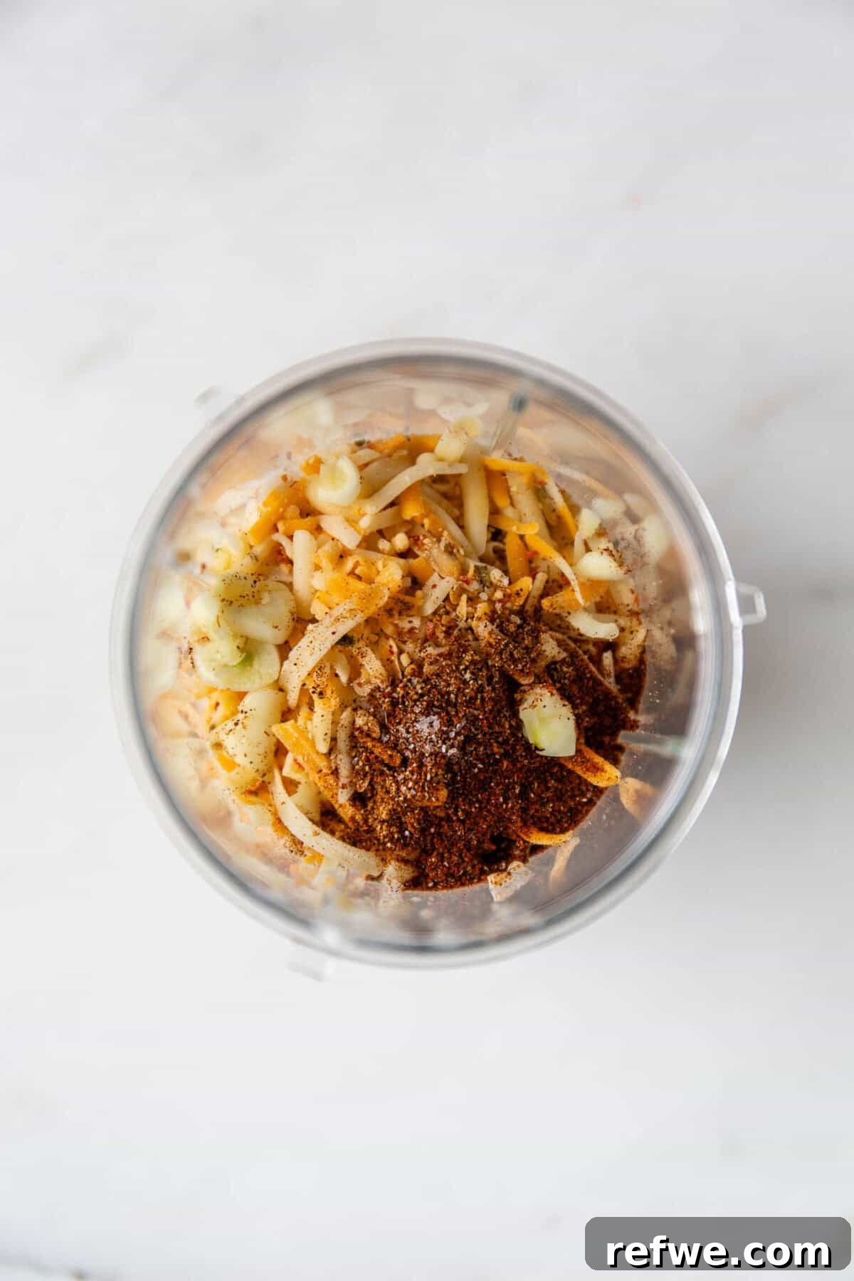 Whipped Cottage Queso Dip 4 All ingredients—cottage cheese, shredded cheese, spices, and fresh garlic—placed in a small blender container, ready for processing.
