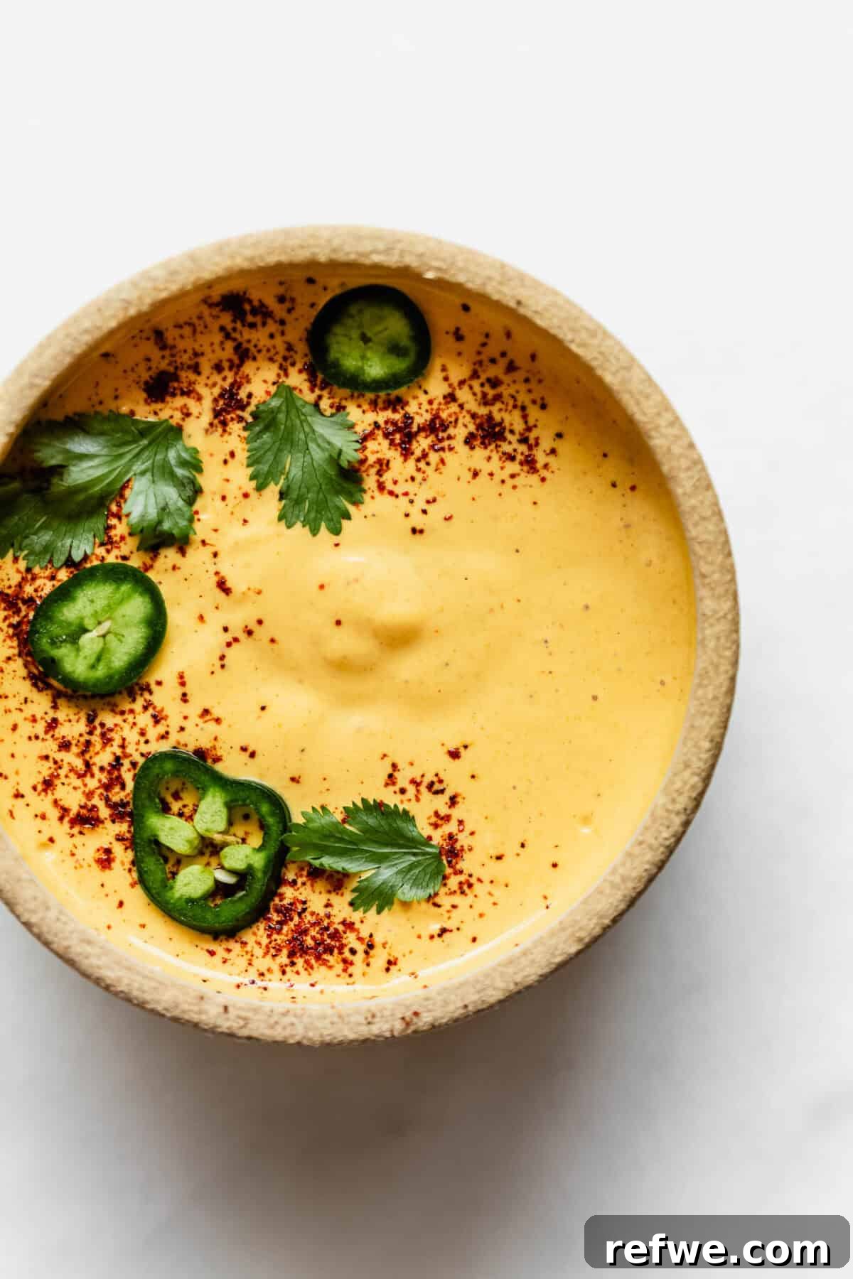 Whipped Cottage Queso Dip 6 Finished cottage cheese queso dip in a serving bowl, garnished with vibrant sliced jalapeños and fresh cilantro for an appealing presentation.