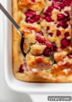 A spoonful of protein pancake bowl with raspberries, showcasing the fluffy texture and vibrant toppings.