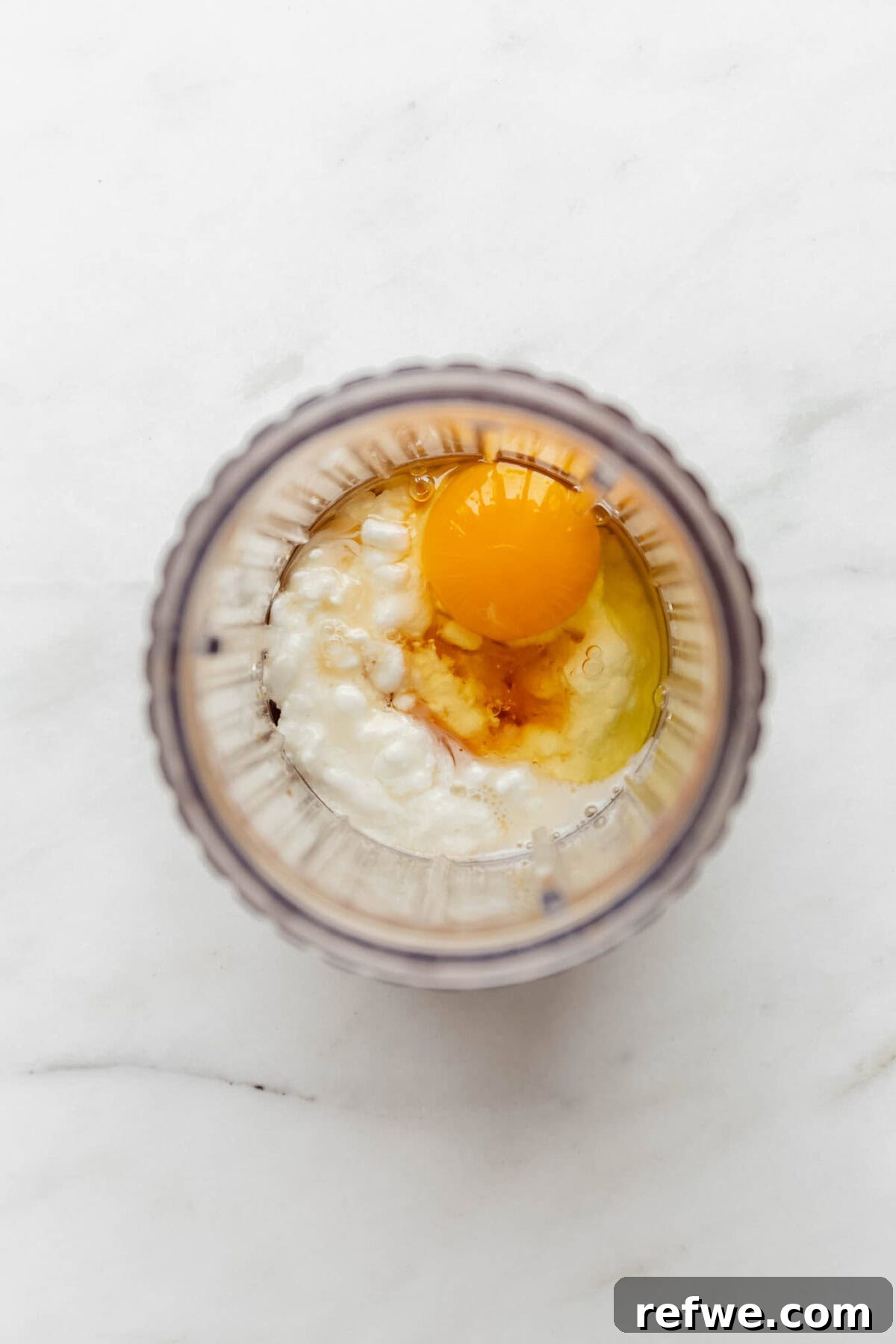 Peak Performance Pancake Bowl 4 Egg, cottage cheese, oats, and maple syrup are perfectly measured and placed inside a blender container, ready for the first step of preparation.
