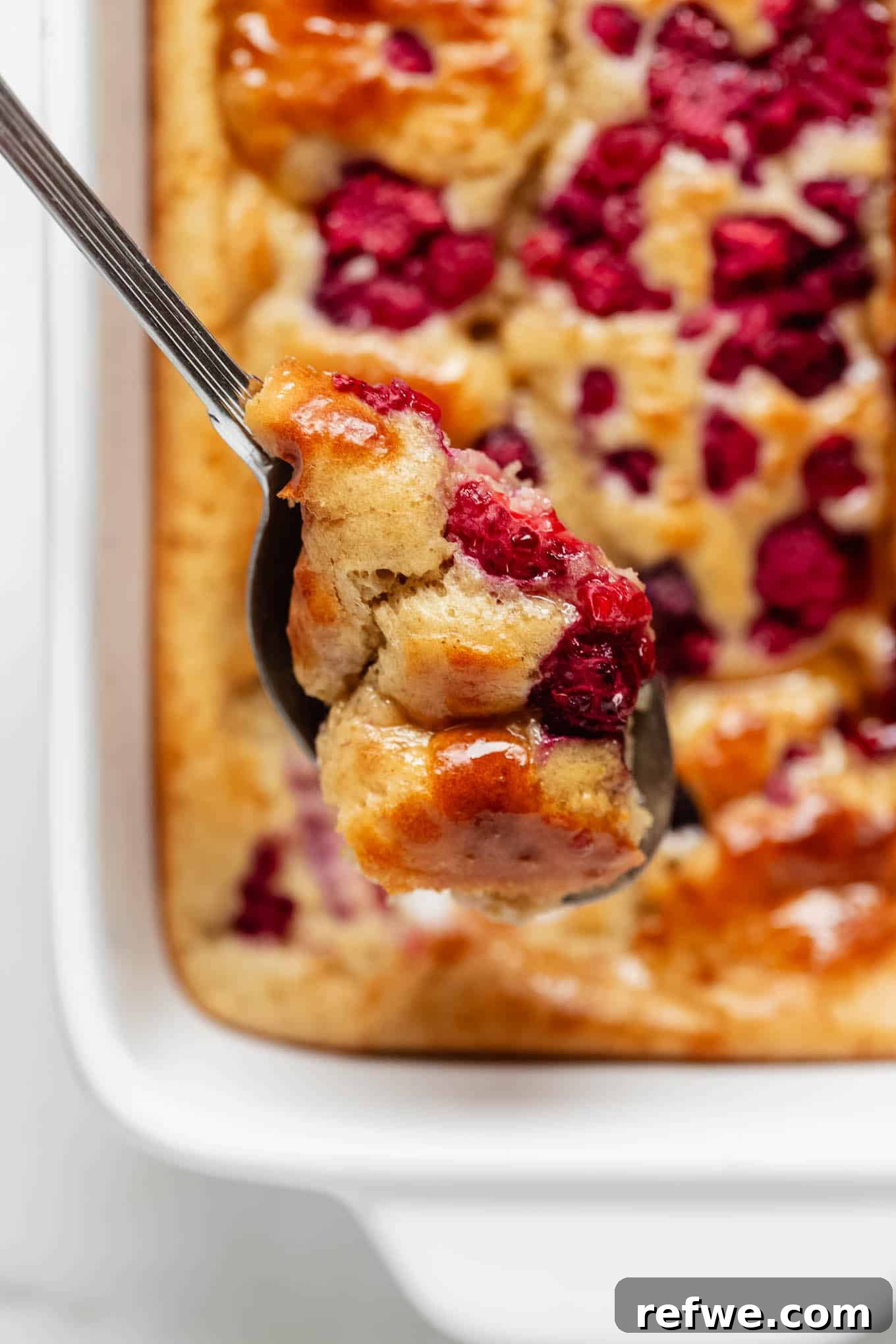 Peak Performance Pancake Bowl 9 A close-up shot of a spoonful of protein pancake bowl, perfectly scooped with a luscious raspberry, ready to be enjoyed.
