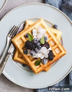 Crispy, fluffy, and healthier Belgian waffles ready to be topped with fresh berries and syrup.