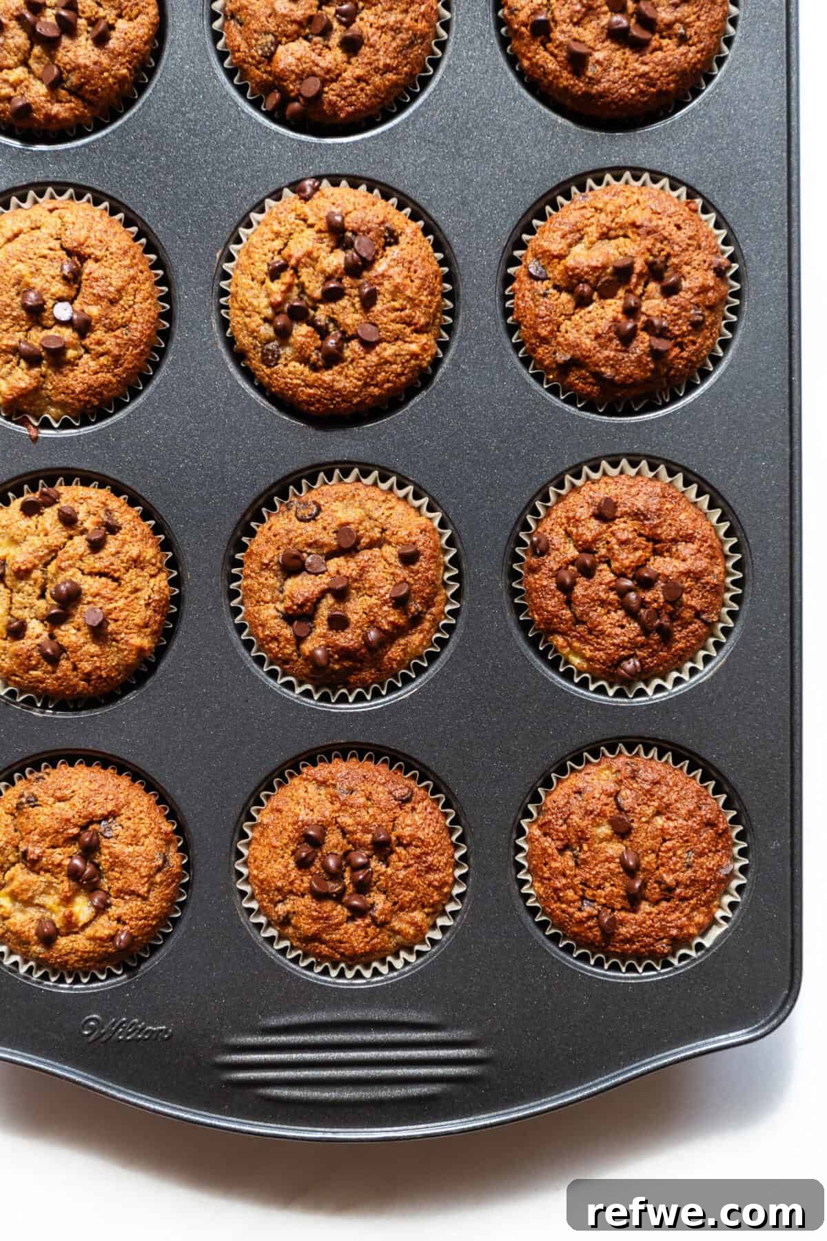 Wholesome Almond Banana Muffins 11 Baked golden brown banana almond flour muffins cooling in a muffin pan, just out of the oven.
