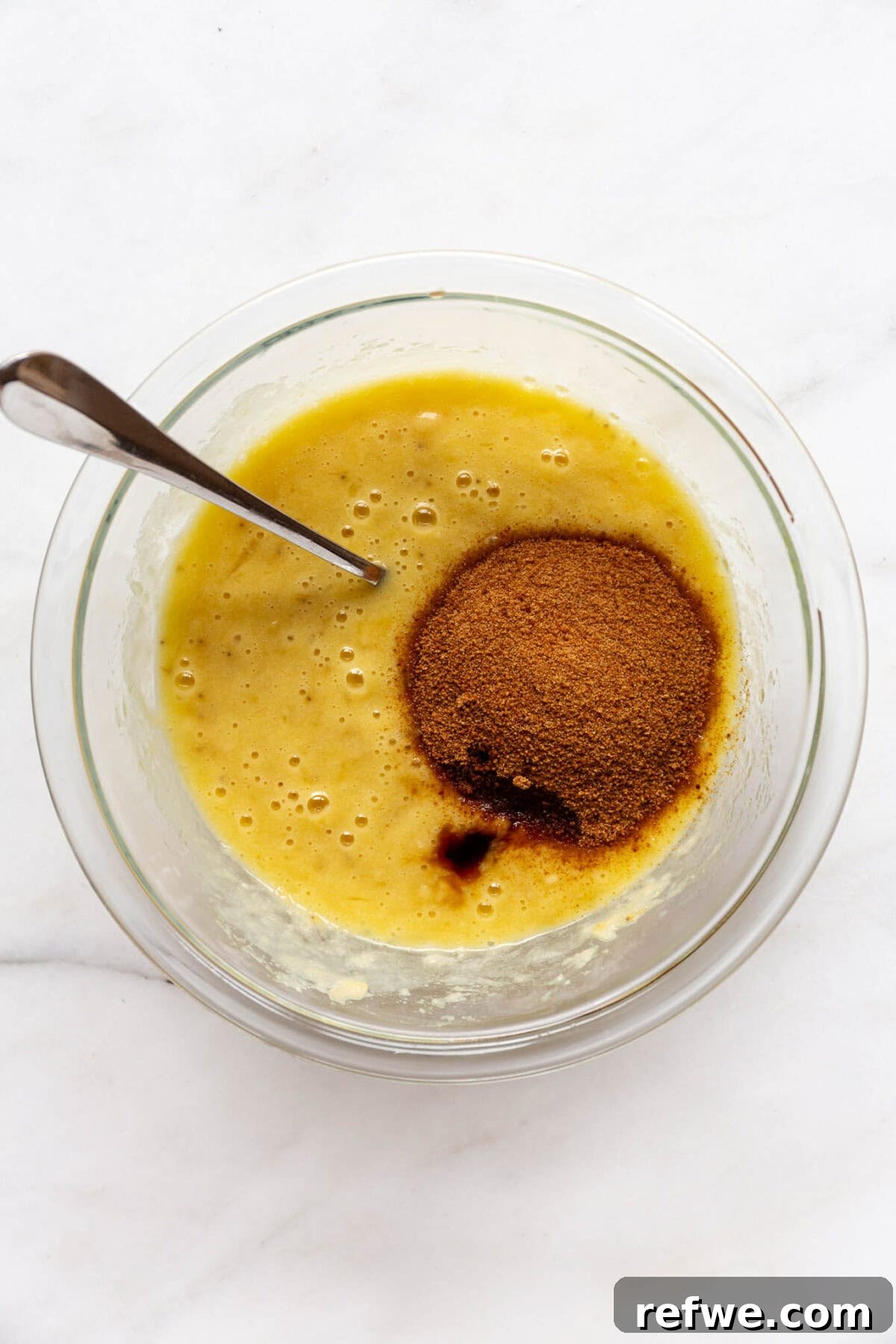 Wholesome Almond Banana Muffins 6 Mashed banana and egg mixture combined with coconut sugar in a bowl, stirred until smooth.