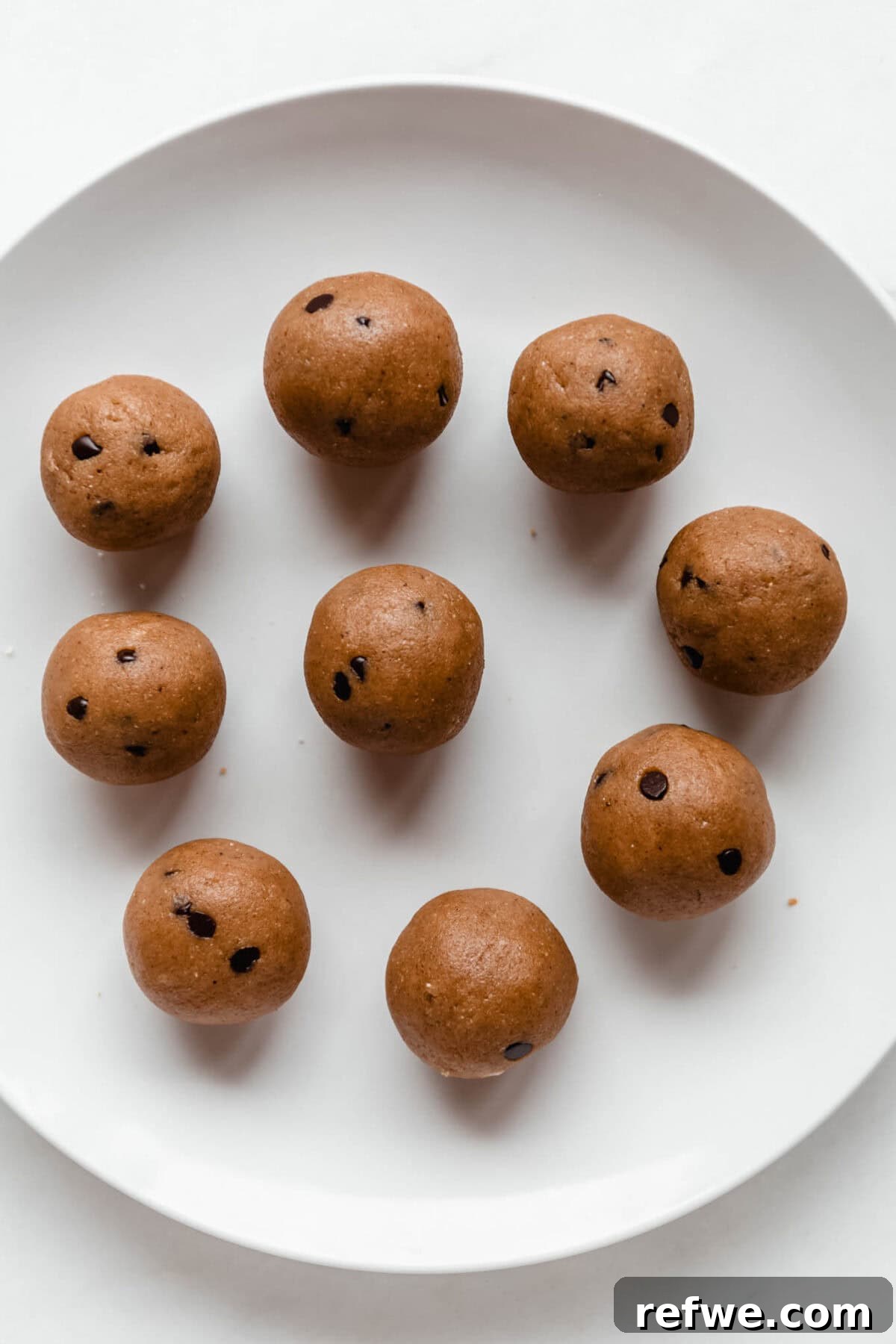 Freshly rolled banana protein balls with chocolate chips, arranged neatly on a white plate.
