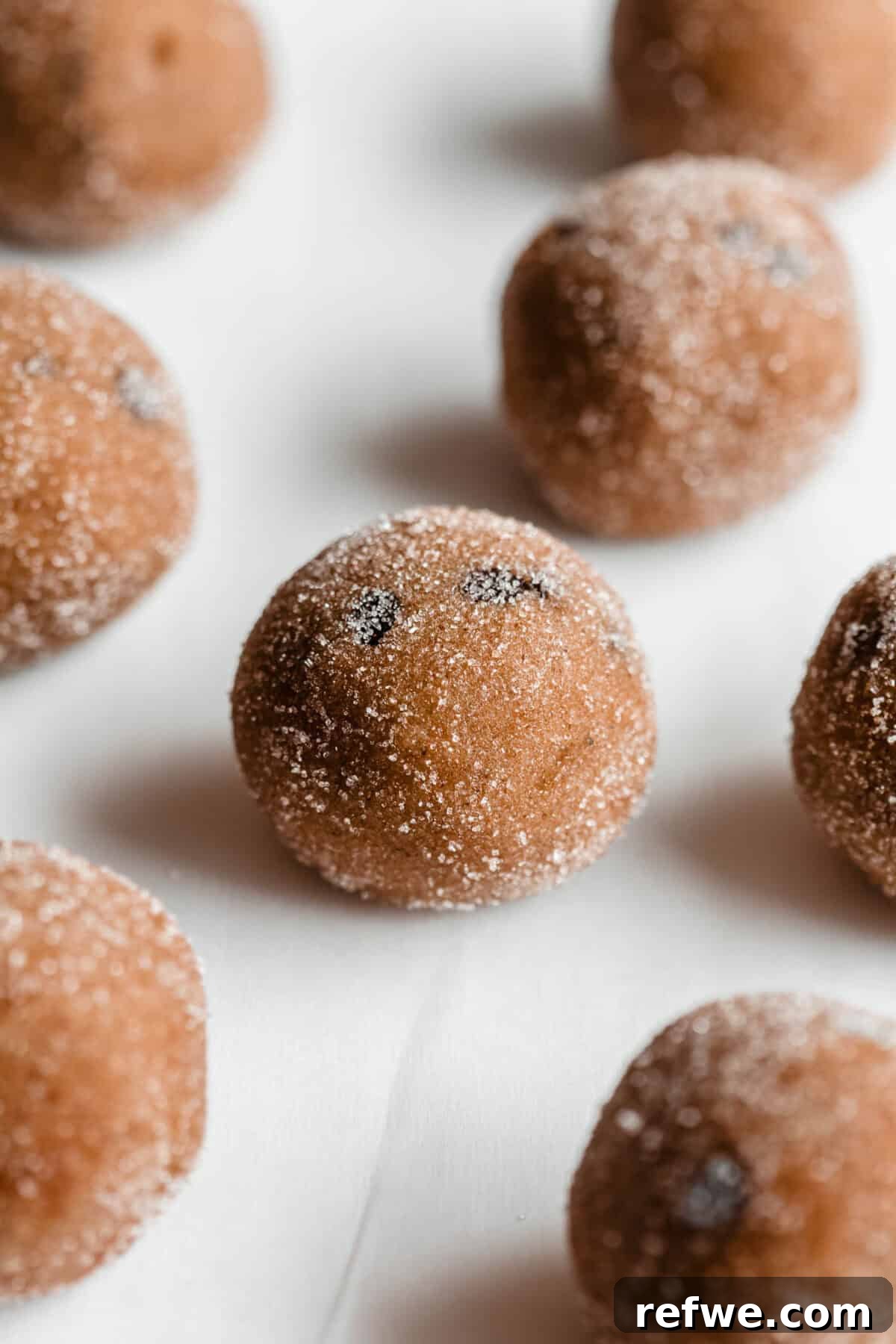 A plate of banana protein balls coated in cinnamon sugar, resting on parchment paper.