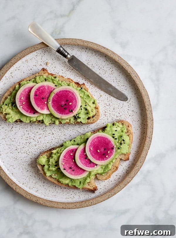 Sunrise Avocado Toast with Ruby Radish Slices 2 A beautifully plated smashed avocado toast topped with vibrant pink watermelon radish slices and sesame seeds, perfect for a healthy breakfast or snack.