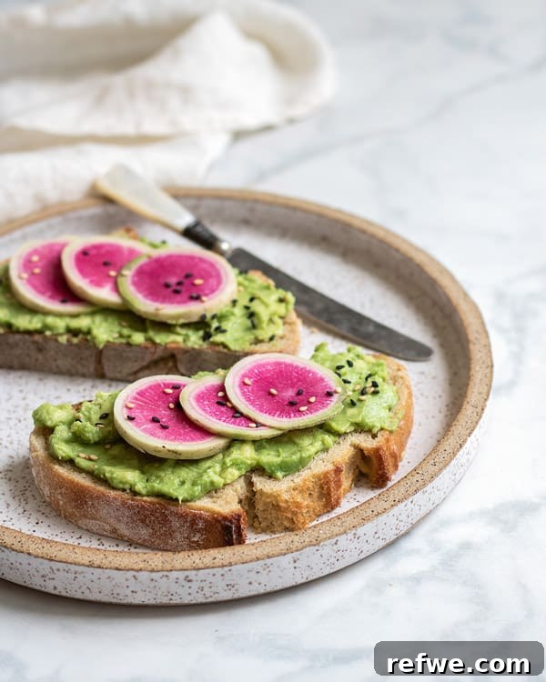 Sunrise Avocado Toast with Ruby Radish Slices 4 A close-up shot of a single slice of smashed avocado toast, showcasing the creamy avocado, vibrant watermelon radish, and a sprinkle of black sesame seeds.