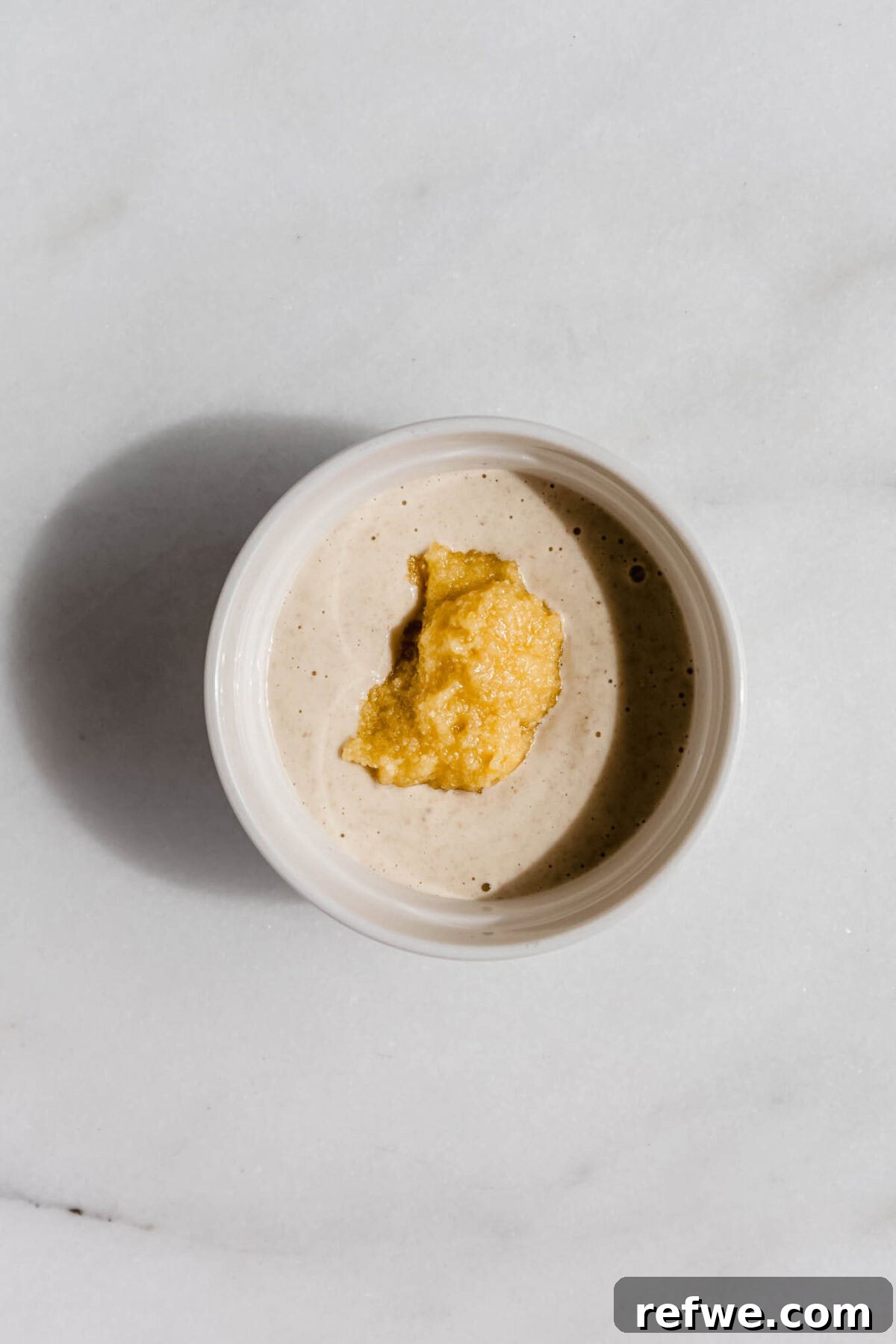 Oat batter being poured into ramekins, then a scoop of almond paste placed in the center.