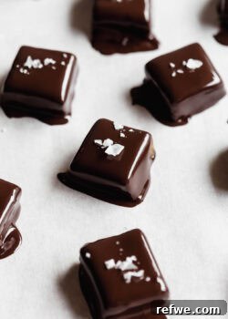 Date caramels dipped in melted dark chocolate topped with salt, ready to be served.