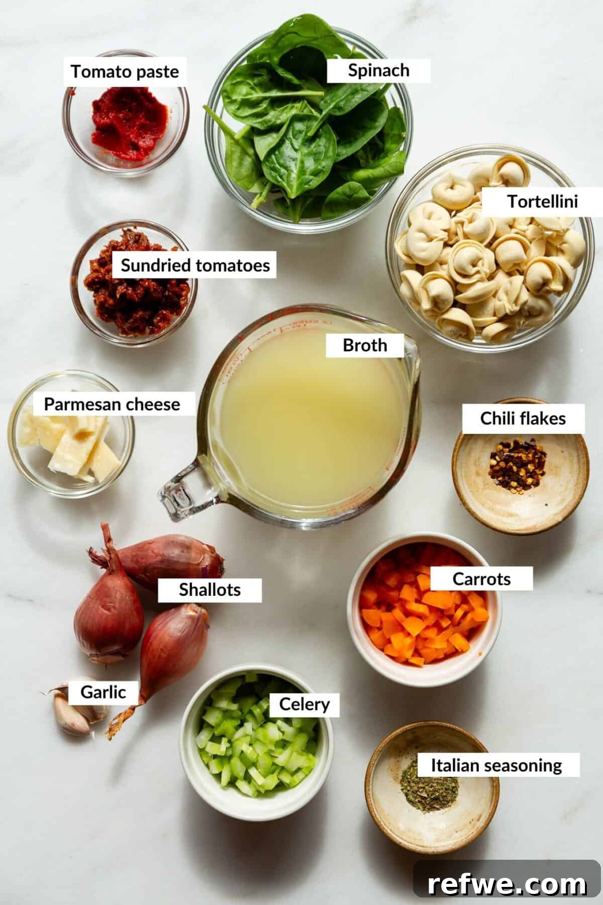 Velvety Tuscan Tortellini Soup 3 Assorted fresh ingredients laid out on a wooden surface, including tortellini, sun-dried tomatoes, spinach, shallots, garlic, and broth, ready for Tuscan Tortellini Soup.