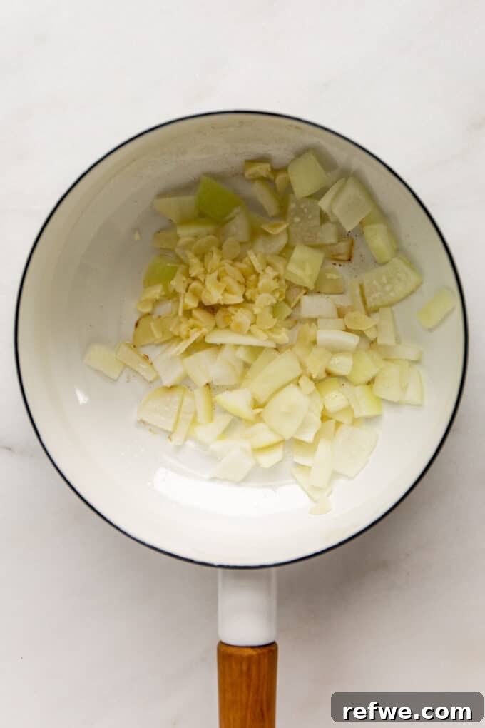 Fragrant Moroccan Chickpea Stew 3 Sautéed garlic and onion starting to soften in a white pot, building the stew's aromatic base.