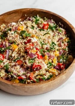 A vibrant roasted vegetable quinoa salad served in an elegant wood bowl.