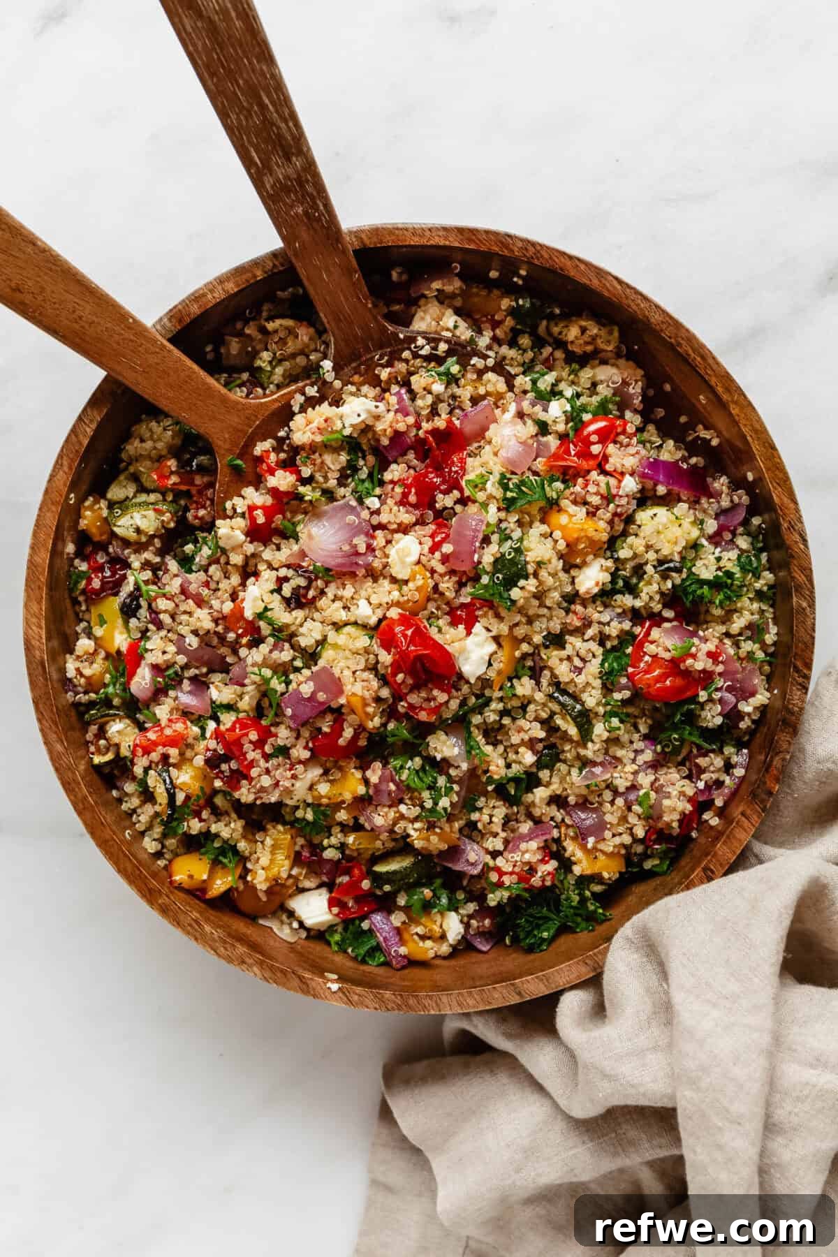Vibrant Roasted Vegetable Quinoa Salad 8 A beautifully presented wood bowl of roasted vegetable quinoa salad, accompanied by elegant wood serving spoons, highlighting its appealing texture and colors.