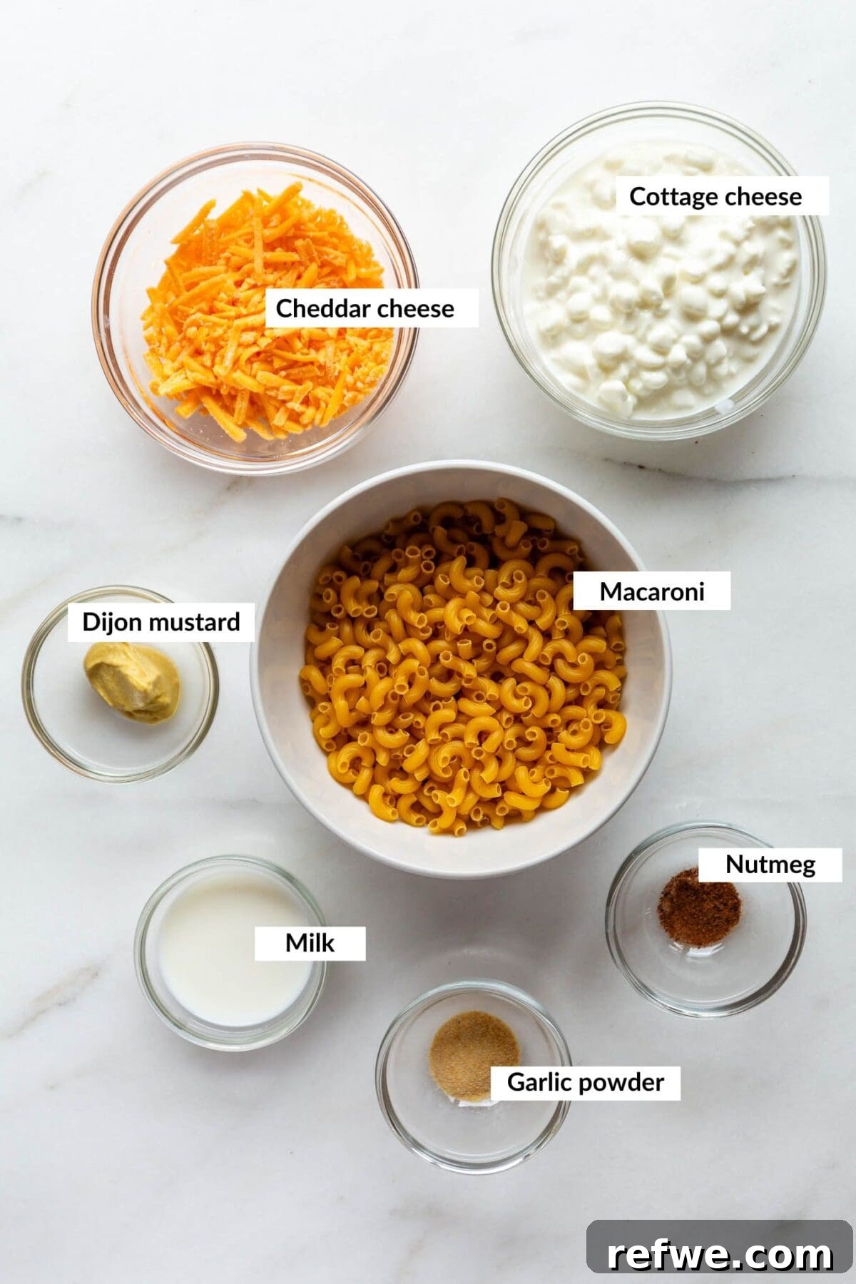 15-Minute Cottage Cheese Mac & Cheese Delight 3 A vibrant selection of ingredients laid out, including cottage cheese, shredded cheddar, pasta, and spices, for a delicious mac and cheese.