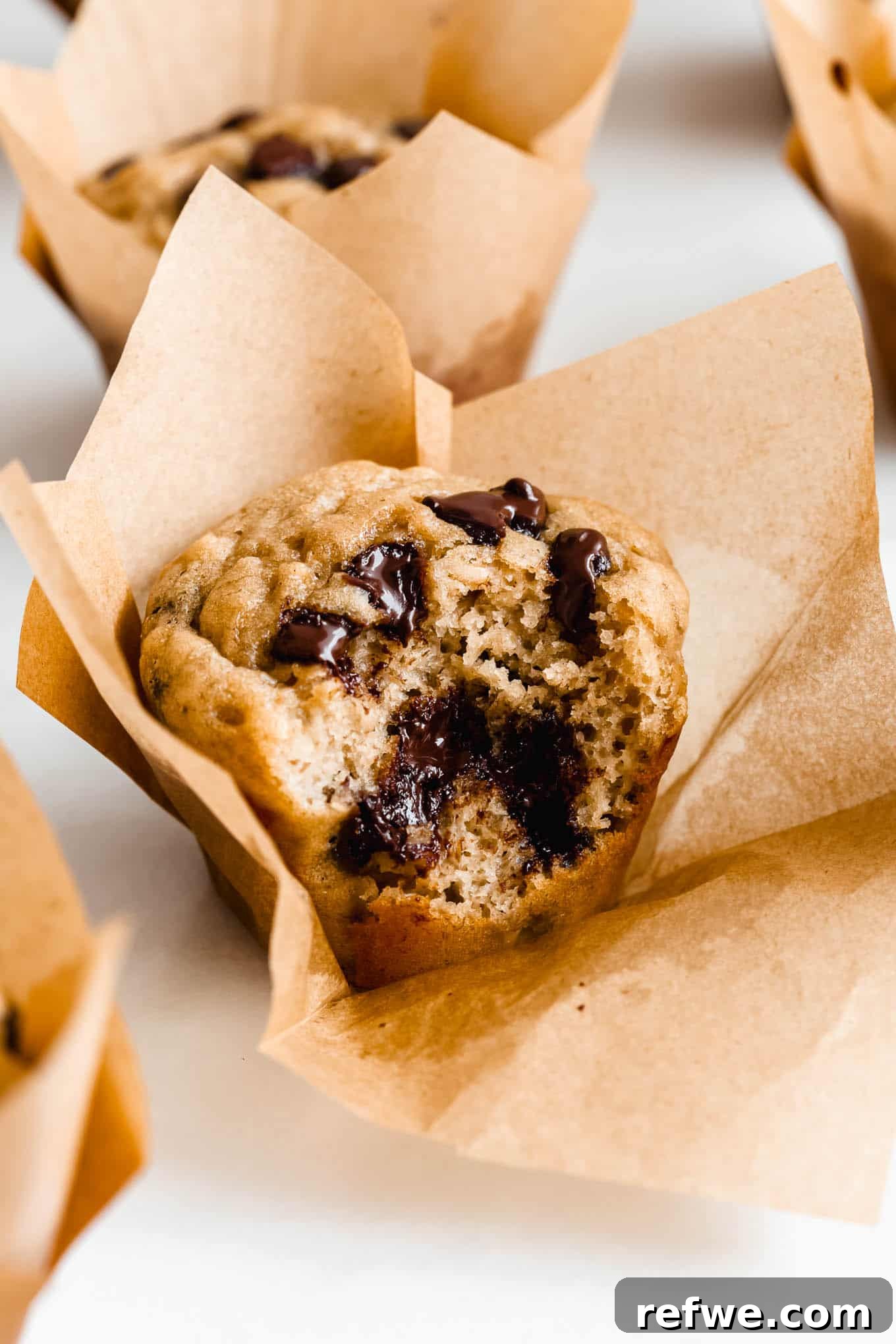 A perfectly baked protein banana muffin with a delightful bite taken out of it, revealing its fluffy interior.