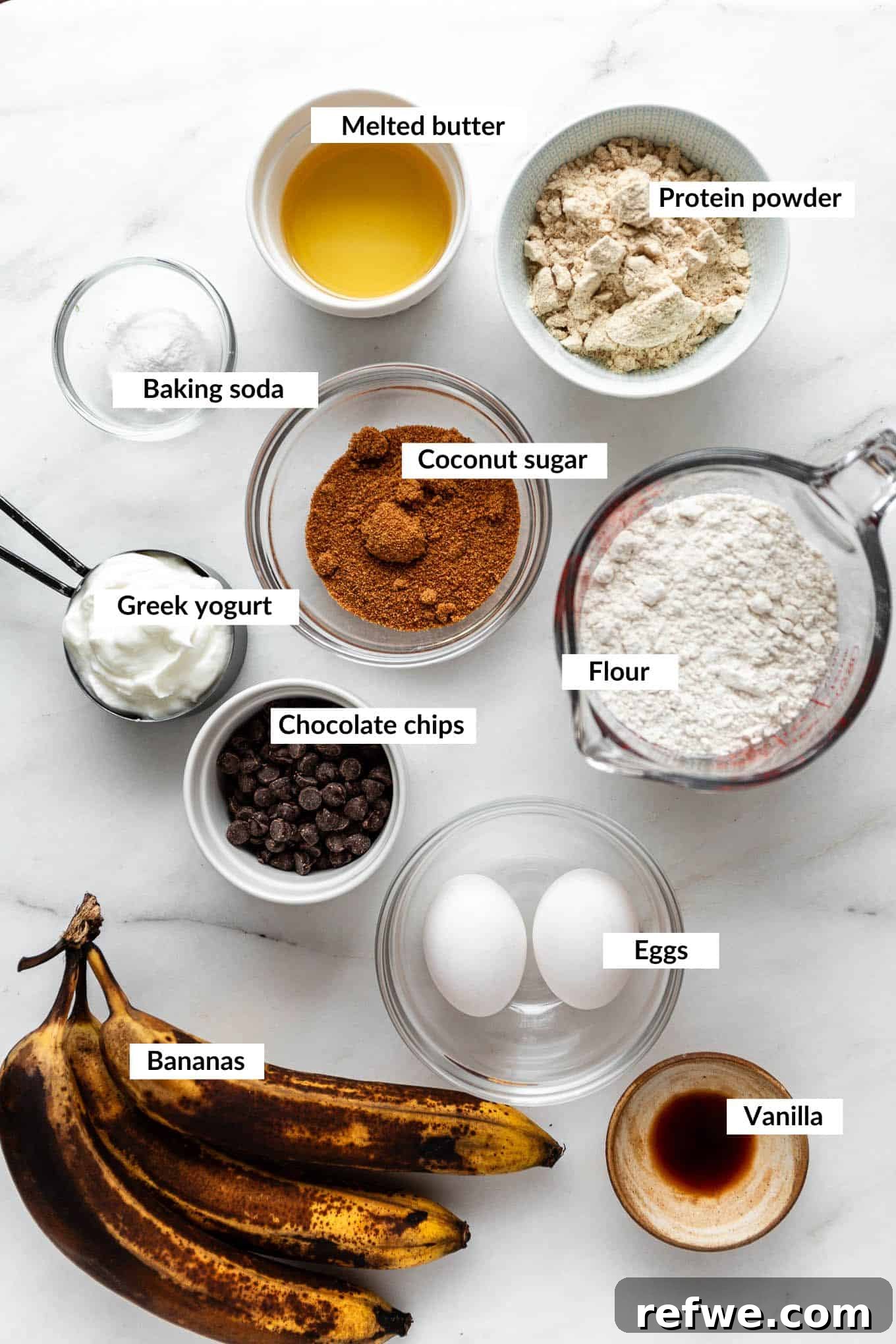 A flat lay of fresh ingredients laid out for making protein banana muffins, including ripe bananas, flour, eggs, and yogurt.