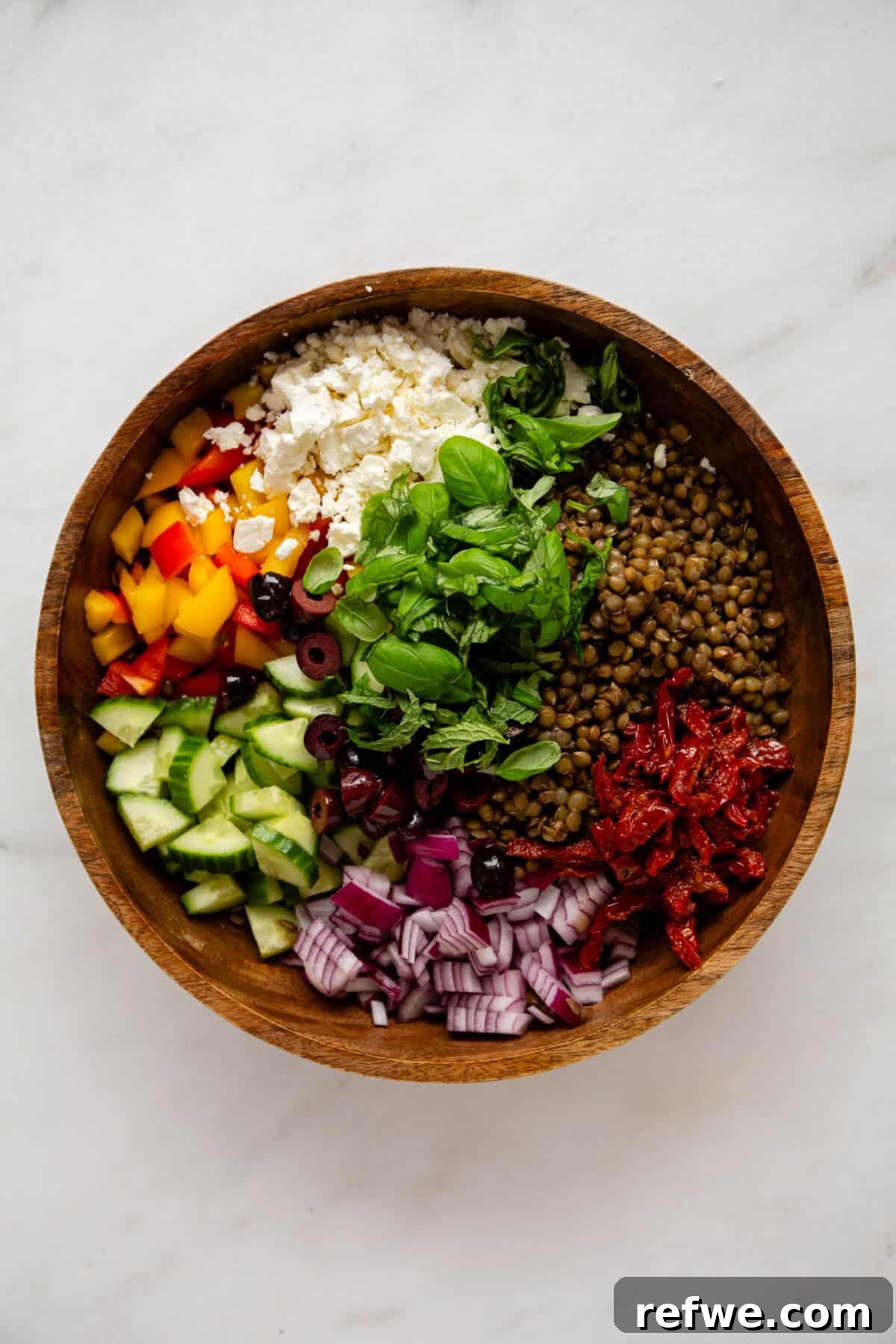 Vibrant Mediterranean Lentil Salad 4 All the fresh ingredients for Mediterranean lentil salad including lentils, colorful vegetables, aromatic herbs, and creamy feta cheese, perfectly portioned and ready for mixing in a large wood bowl.