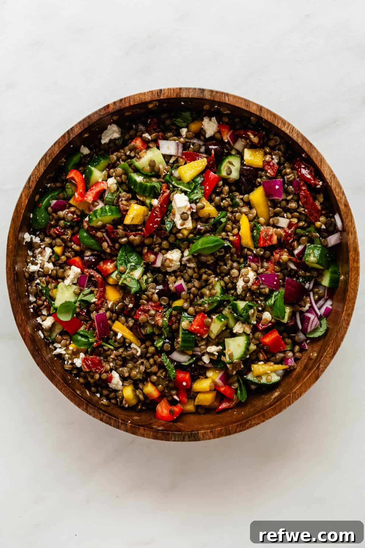 Vibrant Mediterranean Lentil Salad 5 The finished Mediterranean lentil salad, beautifully mixed with the dressing, showcasing its vibrant colors and inviting textures in a rustic wood bowl, ready to be served.