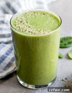 Green smoothie in a glass with a straw, garnished with mint